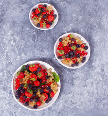 Healthy mixed berry with strawberry, blackberry, red and white currant on the different plates on concrete background. Top view. Copy space.