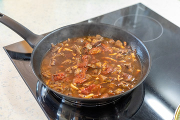 Cooking pork with carrot on stove