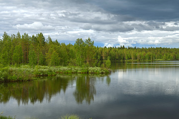 Fototapeta na wymiar Northern forest lake with reflection of black clouds in water in Finnish Lapland. Kuusamo