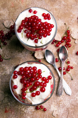 Healthy dessert with organic red currants, fresh yogurt and corn flakes. Dietary breakfast on a brown background