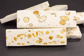 heap of white nougat with peanuts and orange peel and almonds