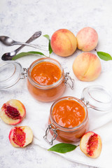 Homemade peach jam with organic fruit. Sweet preserves on a light background