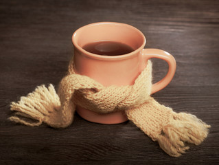 Healing cup of tea in a scarf on a wooden background