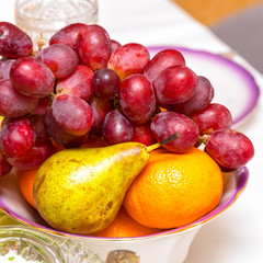 Naklejka na ściany i meble A bunch of grapes, pear and orange on the plate