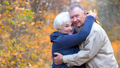 Senior man and woman hugging in an autumn park