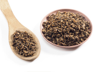 Fermented granular tea from Cherry (Cerasus) leaves in clay plate with spoon on white background