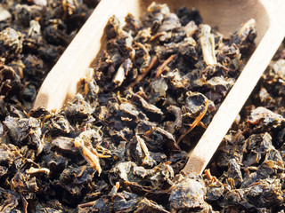 Fermented granular tea from Cherry (Cerasus) leaves in wooden scoop