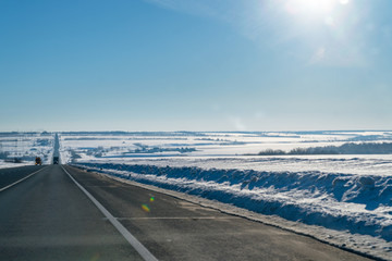 Winter road on the background of the sun in blue sky
