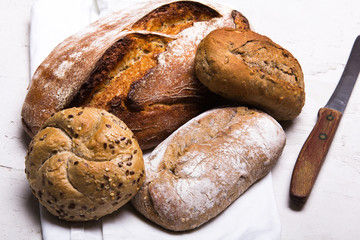 Tasty dark bread and buns  on white background, copy space. Bakery products, wholemeal bread and brown whole wheat buns