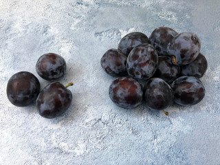 Fresh, ripe, blue-violet plums over concrete background.
