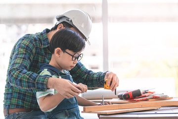 Little Boy is learning to work on wood and be a builder from his craftman father