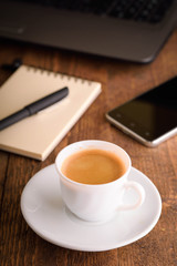  Laptop (notebook) mobile phone (smartphone) and notepad with pen on old wooden table. Work place modern.Cup of coffee