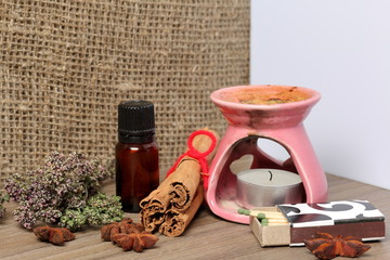 Aromatherapy lamp with candles and accessories. Oil in a bottle and matches. Nearby lies a bunch of dry thyme, anise and cinnamon sticks.