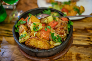 Traditional Georgian family food ojakhuri, fried meat with potatoes and vegetables in a ceramic pot close-up, tasty cuisine