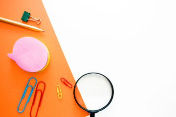 simple pencil, paper clips, magnifier, office stationery in the form of a layout on top of a double background of white and orange