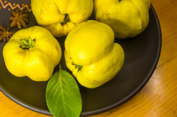 large yellow quince fruits on a ceramic plate, with anise, cinnamon, and walnuts