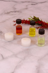 Essential oils and white candles over marble background with copy space in portrait position 