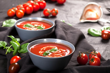 Traditional spanish cold tomato soup gazpacho in a bowl over black stone background.