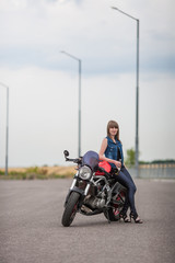 Plakat sexy biker woman sitting on a vintage custom motorcycle. Girl biker with perfect fit slim body. The spirit of freedom and independence. Beautiful brave woman is leaning on her motobike on highway