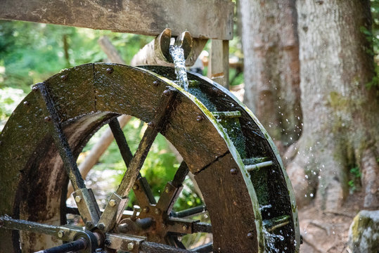 A waterwheel in the forest with motion blur added.