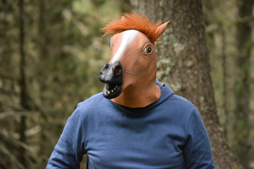 Hombre con cabeza de caballo en un bosque verde y frondoso. © Momo Estudi