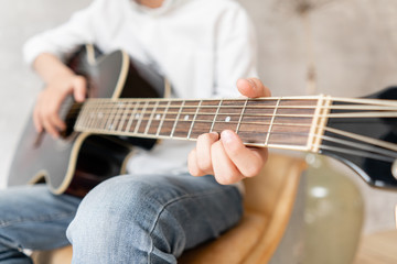 Fototapeta na wymiar Closeup of wooden guitar in hands of young boy in casual clothes