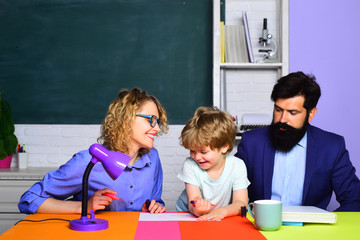 Cute pupil and his father and mother in classroom. September 1. School education. Ready to study. Happy schoolboy at lesson. Child from elementary school with parents in school. Beginning of lessons.