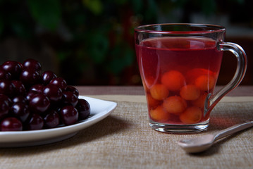 Cherry on a white plate and homemade fresh compote of cherries on a wooden table.