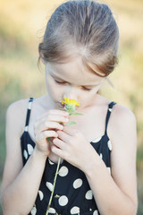 Beautiful, little girl holds in her hands yellow flowers of sunflower.