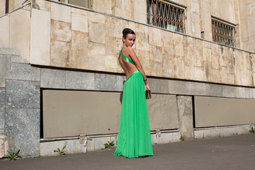 Fototapeta na wymiar elegant woman in green dress posing against a concrete wall