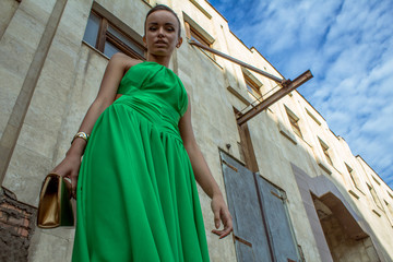 elegant woman in green dress posing against a concrete wall