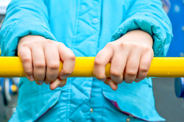 Child hands holding metal bar of children sports equipment on playground - 282124316