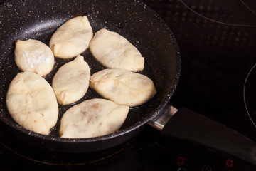 Meat pies, pan-fried in boiling oil. small raw pies in a frying pan with hot oil. copy space for text.