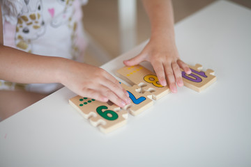 Close up hands of little girl playing with figures while sitting at table 
