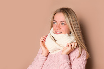 Young woman in winter hat, pink sweater, beige background