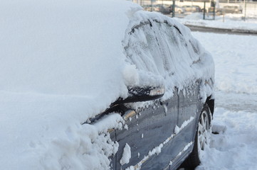 dark blue car covered with snow. Sunny morning day