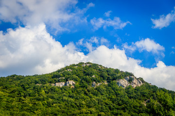 Fototapeta na wymiar Russian mountains. Crimea. Summer mountains background. Forest and mountains in the sun on the background of a cloudy sky above the peninsula of Crimea. Sunny, bright, saturated raster photo