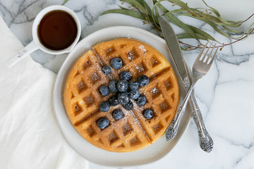 Belgian Waffle with Blueberries and Maple Syrup, Dusted with Powdered Sugar, Flay Lay on Marble Background, Copy Space