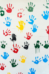 Fototapeta na wymiar hand prints in many colors on a white wall