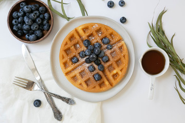 Belgian Waffle with Blueberries and Maple Syrup, Dusted with Powdered Sugar, Flay Lay on White Background, Copy Space