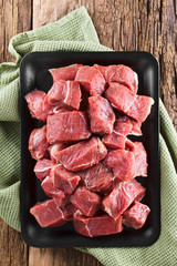 Fresh raw diced red beef meat on cast iron plate photographed overhead