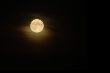 Yellow full moon in dark cloudy sky