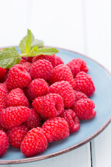 Fresh raspberries in a plate on a  vintage background.