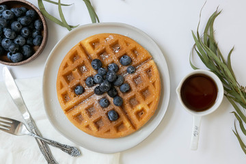 Belgian Waffle with Blueberries and Maple Syrup, Dusted with Powdered Sugar, Flay Lay on White Background, Copy Space