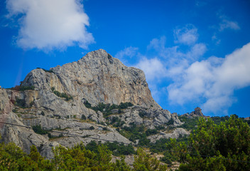 Russian mountains. Crimea. Summer mountains background. Forest and mountains in the sun on the background of a cloudy sky above the peninsula of Crimea. Sunny, bright, saturated raster photo