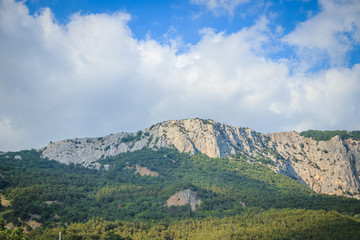 Russian mountains. Crimea. Summer mountains background. Forest and mountains in the sun on the background of a cloudy sky above the peninsula of Crimea. Sunny, bright, saturated raster photo