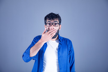 Obraz premium Surprised man closes his mouth on gray background