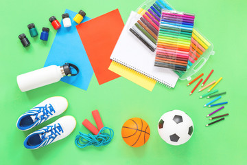 Assorted office or school sets of multicolored stationery school and sport football ball on green background. Flat lay copy space. back to school or creative design education craft concept.