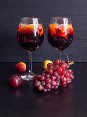 Sangria red wine or punch with fruit and ice in glasses. Homemade refreshing sangria fruit on a rustic wooden table. Spanish cuisine.