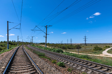Fototapeta na wymiar The summer landscape of the railway in the steppe or prairie with bue sky in sunny weather